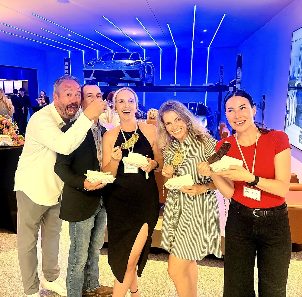 Five guests laughing with their chocolate dipped bananas at an evening event